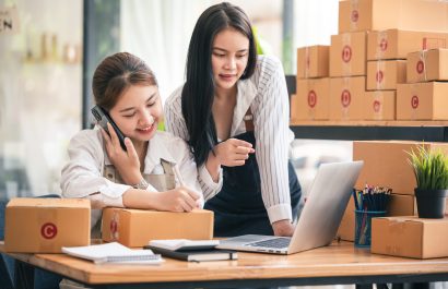 Small start-up business owners using computers and phones at work, salespeople, checking production orders. Pack products to ship to customers, sell ecommerce shipping ideas.